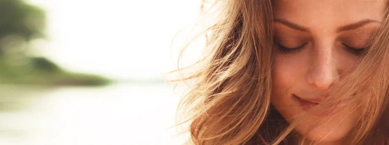 Smiling woman at beach looking downwards