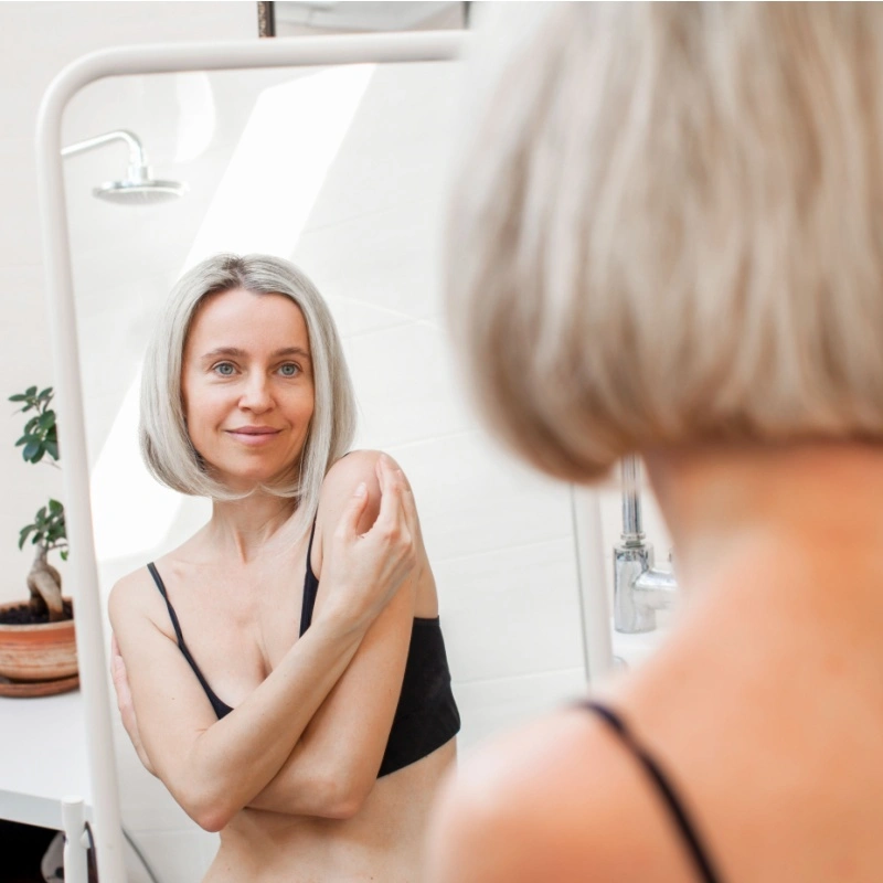 woman looking in the mirror at her body
